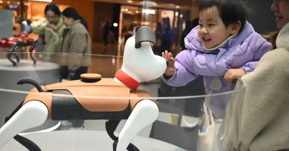 Young child interacting with an AI companion robot toy at a public technology exhibition in China.